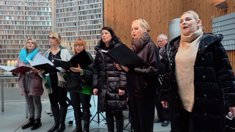Eine Gruppe von Sängern steht in einer Kirche und singt zusammen.